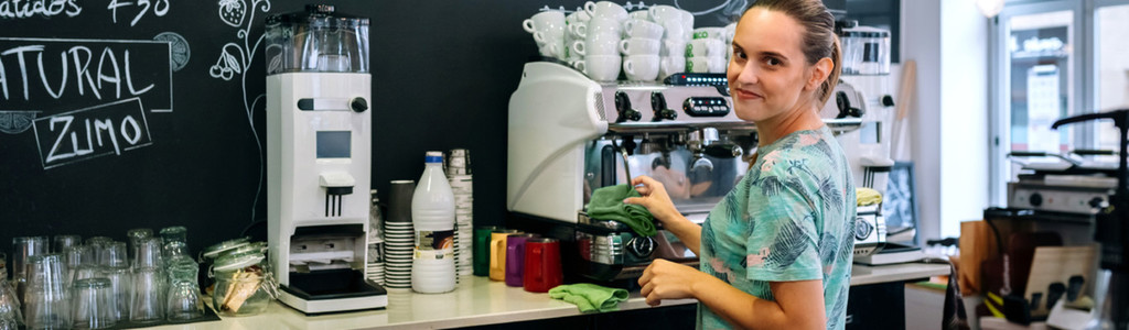 Smiling waitress cleaning coffee maker