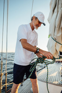 Mature yachtsman adjusting rope
