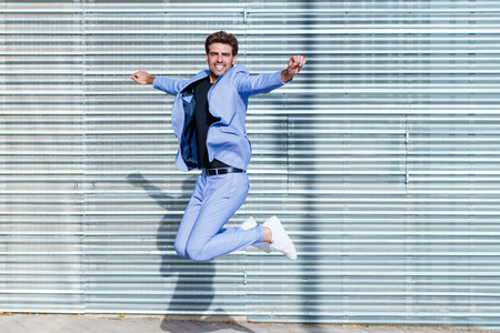 Young man wearing a suit jumping outdoors
