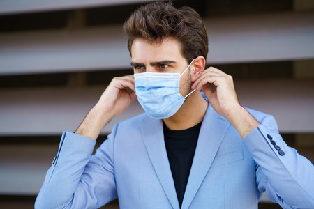 Businessman putting on a surgical mask to protect against the coronavirus
