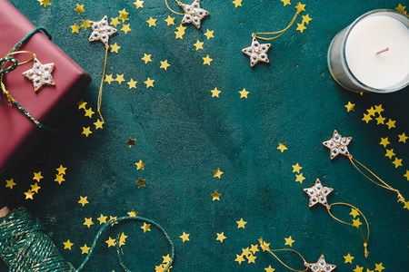 The New Year or Christmas festive flat lay with golden stars over a dark green background Top view copy space