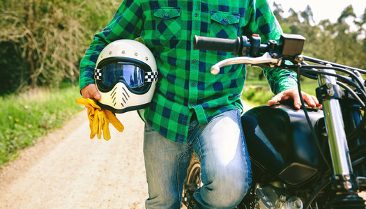 Man posing with motorcycle  helmet and gloves