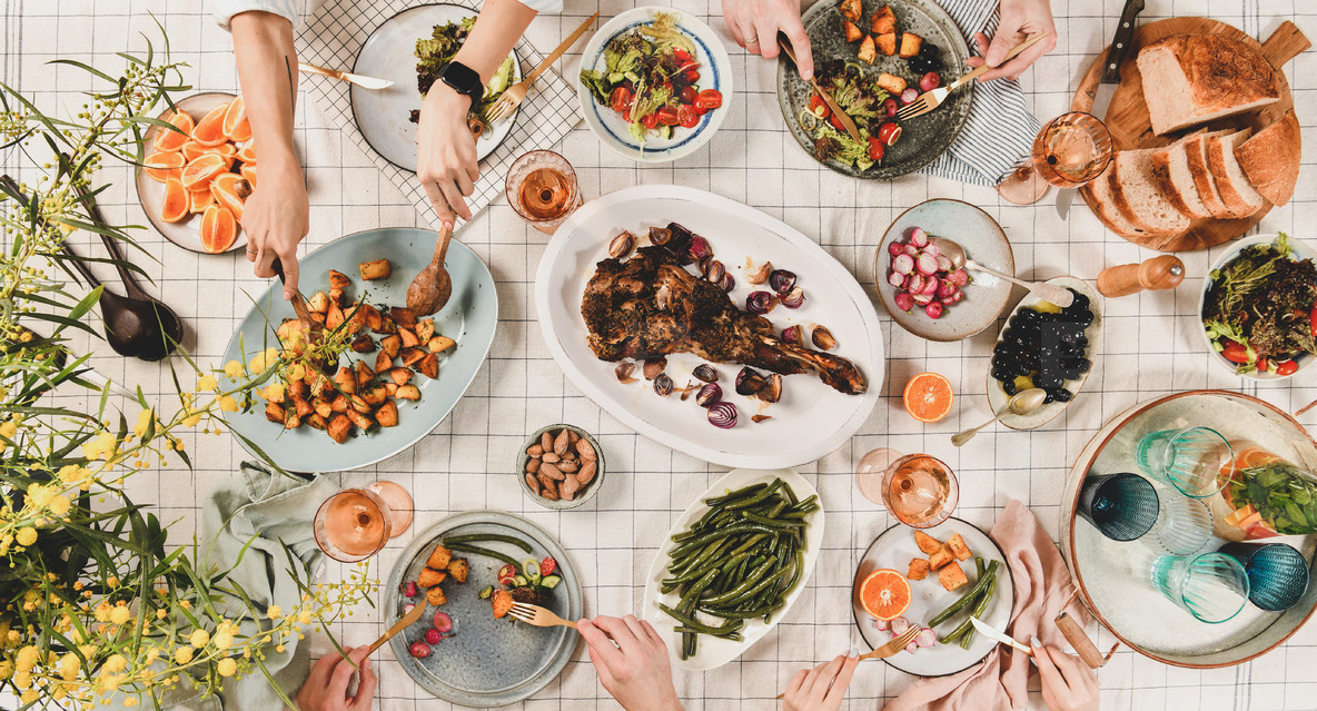 Peoples hands over table with meat salads wine wide composition