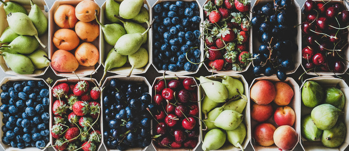 Summer fruit and berry assortment in wooden boxes top view
