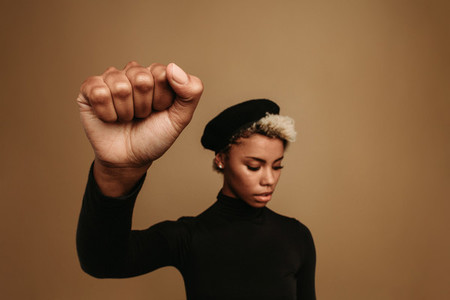 African american woman with raised fist on brown background