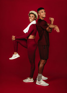 Cheerful fitness couple working out on maroon background