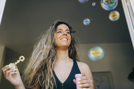 Happy young woman blowing bubbles in doorway