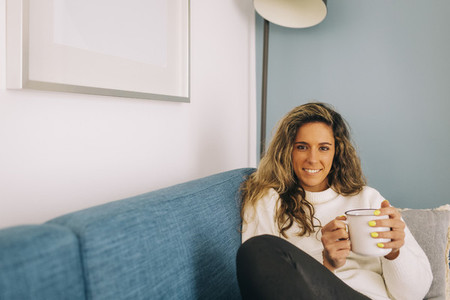 Portrait smiling young woman drinking coffee on sofa
