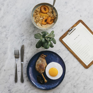 Apricot porridge and confit duck leg and egg on restaurant table