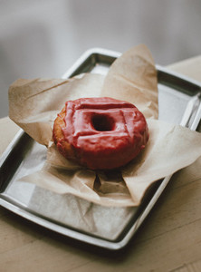 Close up raspberry glazed donut on tray