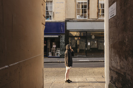Young woman in hoody standing on sunny empty UK