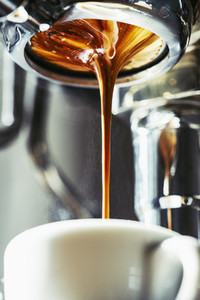 Close up espresso dripping into coffee cup
