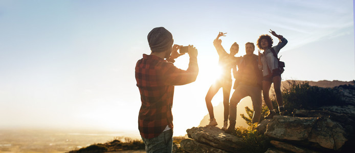 Man photographing his friends on mountain top