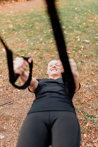 Woman training with trx outside in the park