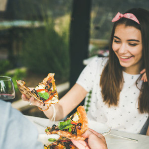 Young caucasian couple eating pizza and drinking wine  square crop