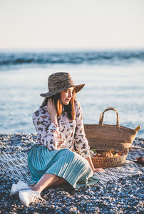 Young woman having picnic at sunset at seaside