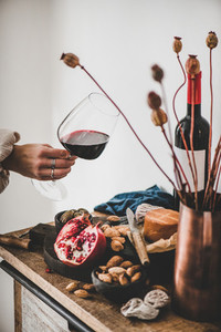 Womans hand with glass of red wine over appetizers