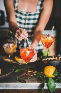 Young woman mixing ingredients in Aperol spritz drink