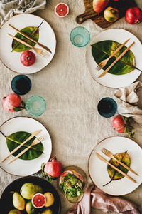 Autumn table setting with seasonal fruits and fallen leaves