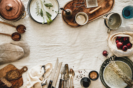 Various kitchen utensils and tablewear over linen tablecloth  copy space