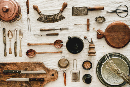 Various kitchen utensils and tablewear over rustic linen tablecloth