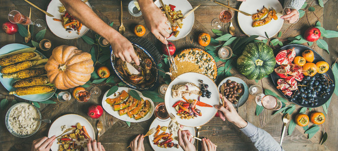 Friends feasting at Thanksgiving Day table with turkey wide composition