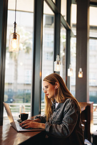 Woman at cafe working on laptop