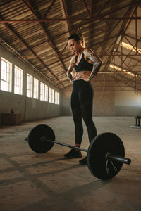 Female exercising with heavy weights inside old warehouse