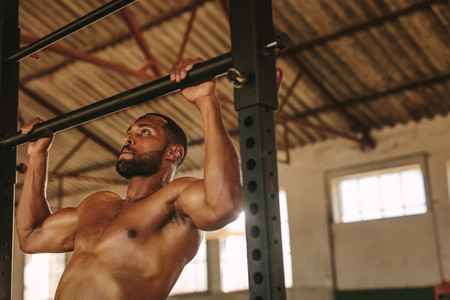 Fit man doing pull up workout inside old warehouse