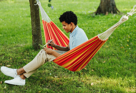 Young man sitting on hammock