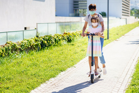 Mother and daughter riding on electric scooter