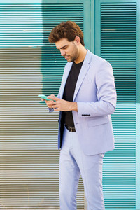 Young man wearing a suit texting with smartphone outdoors