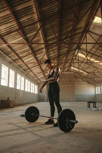 Fitness woman exercise with barbell in old warehouse