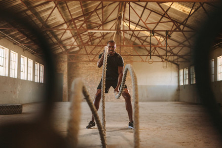 Strong man exercising with battle ropes