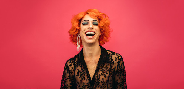 Drag queen laughing on pink background