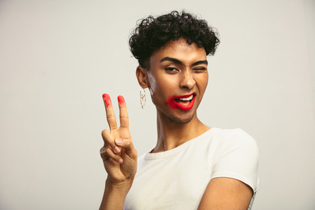 Gay man with smeared lipstick showing peace sign