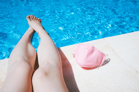 Woman legs in a swimming pool near a protective pink mask