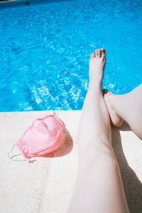 Woman legs in a swimming pool near a protective pink mask