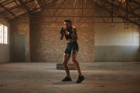 Woman shadow boxing in empty factory shade