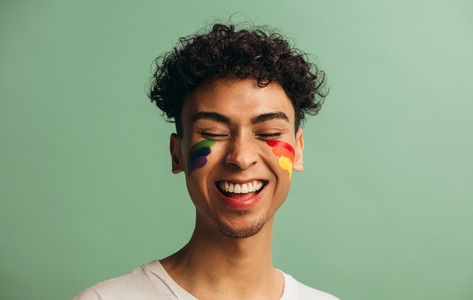 Cheerful gay man with rainbow face paint