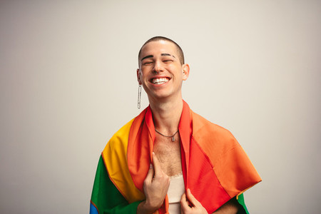 Cheerful transgender man with gay pride flag
