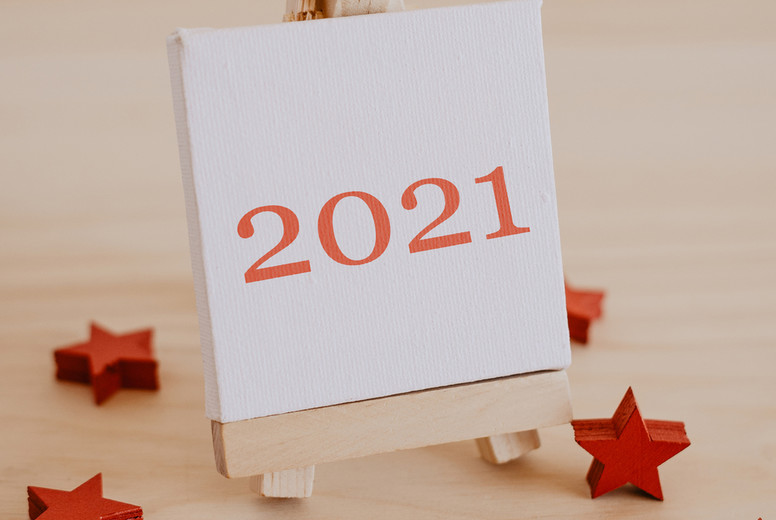 2021 written on the canvas of a painting easel with decorative red stars.