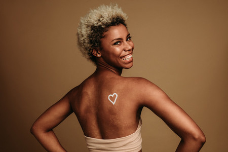 Smiling african american woman standing on brown background