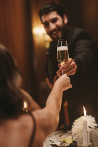 Handsome guy giving a champagne to a friend at dinner party