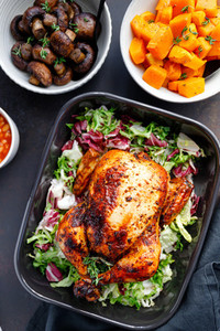 Top view of a whole roasted chicken served with fresh salad in black pan  Thanksgiving or family dinner celebration cooking concept
