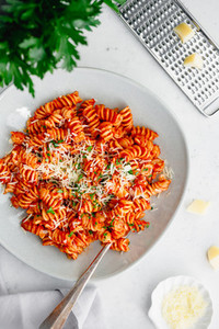 Top view of fusilli pasta with tomato sauce and parmesan cheese