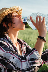 Farmer woman drinking water from plastic bottle during harvesting