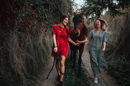 Two women friends chatting and taking a ride with their horse through the countryside
