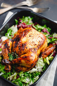 Top view of a whole roasted chicken served with fresh salad in black pan Thanksgiving or family dinner celebration cooking concept