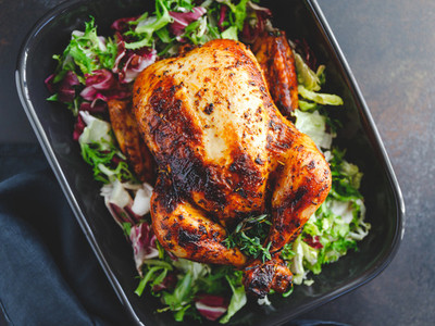 Top view of a whole roasted chicken served with fresh salad in black pan  Thanksgiving or family dinner celebration cooking concept
